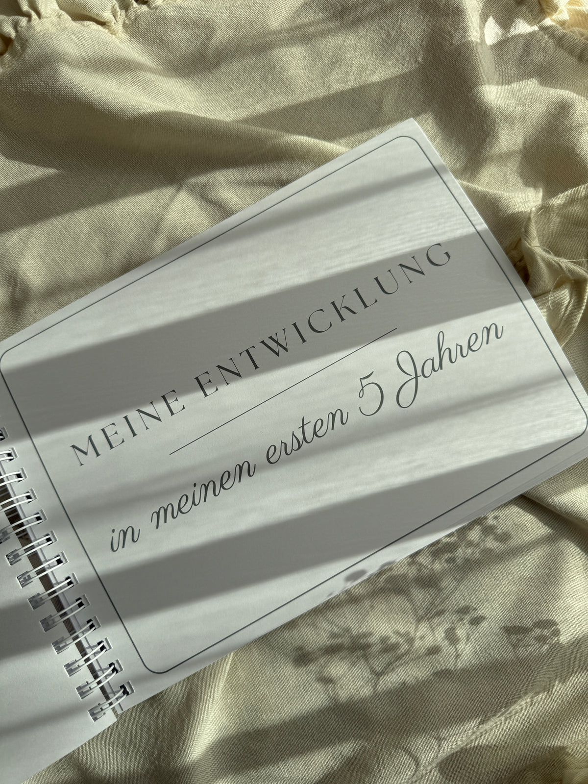 Aufgeschlagene Kapitelseite „Meine Entwicklung in meinen ersten 5 Jahren" mit Wire-O-Spiralbindung, die das Album flach aufliegen lässt
